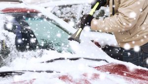 A man uses winter car accessories in the snow