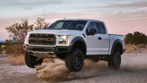 A white Ford Raptor slings some dirt off-roading