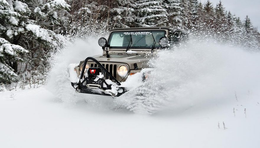 A Jeep Wrangler, one of the best winter SUVs, tackles a snowy road