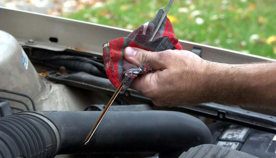 A man checks to see if there is too much oil in car