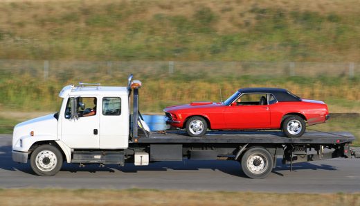 Tow Truck Hauling A New Red Car Americans love their vehicles. Life without a vehicle is hard to comprehend. But sometimes, it leaves you looking for a car towing service